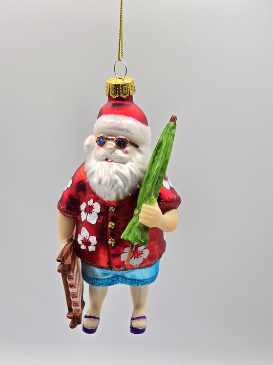 Weihnachtsmann mit Hawaii Hemd auf dem Weg zum Strand mit Liege & Schirm